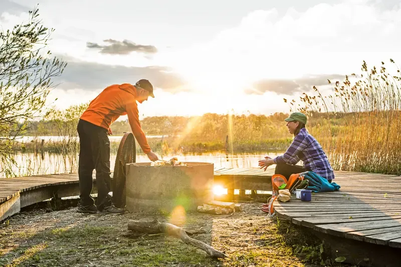 En man och en kvinna som grillar vid den arkitektritade fågelplattformen Slingra Dig.