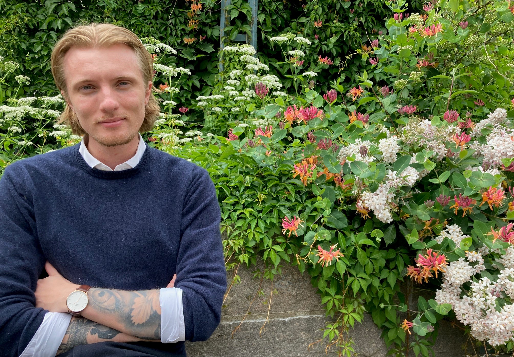 Byggnadsinspektör Noah Olsson framför en rabatt med mur.