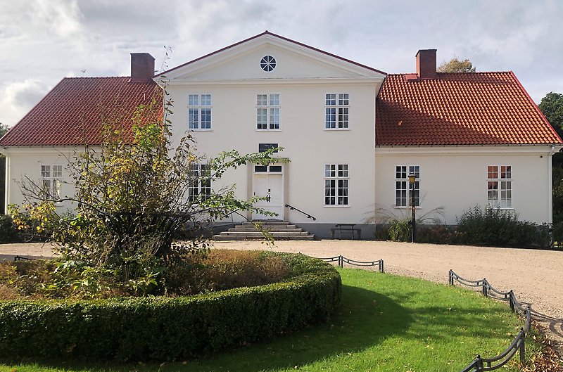 Gammal herrgårdsbyggnad i ljusgul puts som är huvudbyggnaden på Hässleholmsgården.