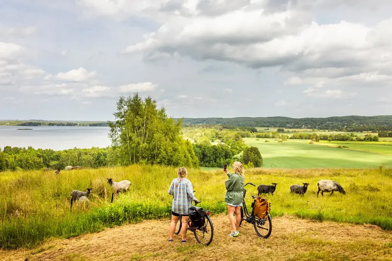 Kvinna som leder en cykel på stranden vid Finjasjön.