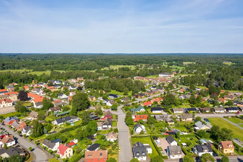 Ett grönt villaområde ovanifrån mot blå himmel.
