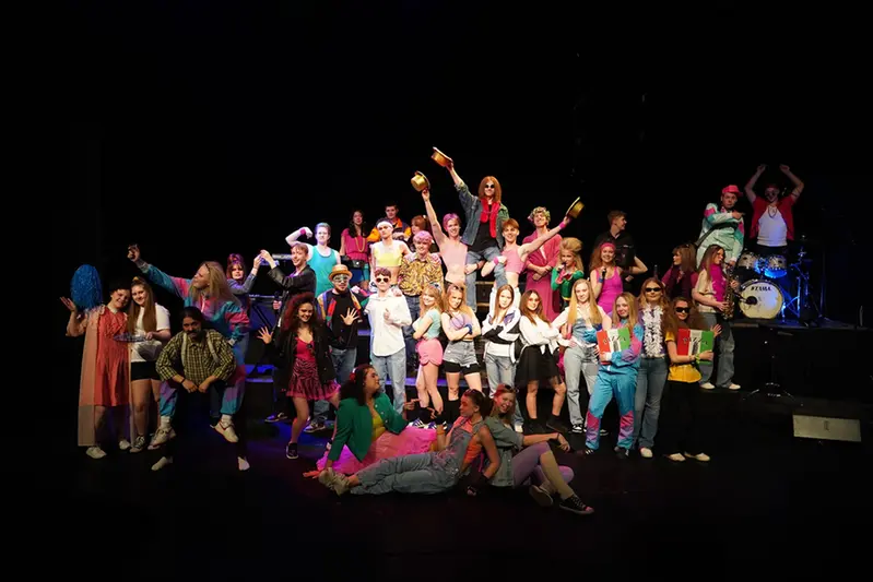 flera elever som står på scenen och sjunger
