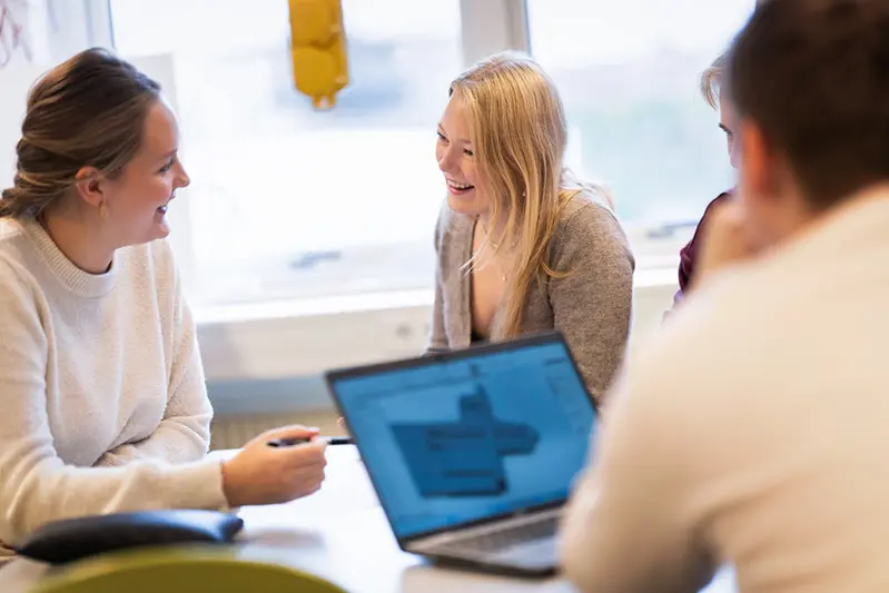 tre elever som arbetar i en sal med datorer