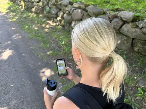 Ung tjej vandrar och tittar på kartan i mobilen
