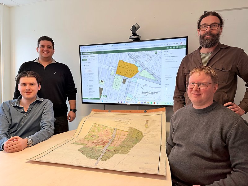 Fyra medarbetare på miljö- och stadsbyggnadsförvaltningen samt lantmäteriet. På bordet ligger en detaljplanekarta av papper, bakom dem syns en digitaliserad detaljplan.